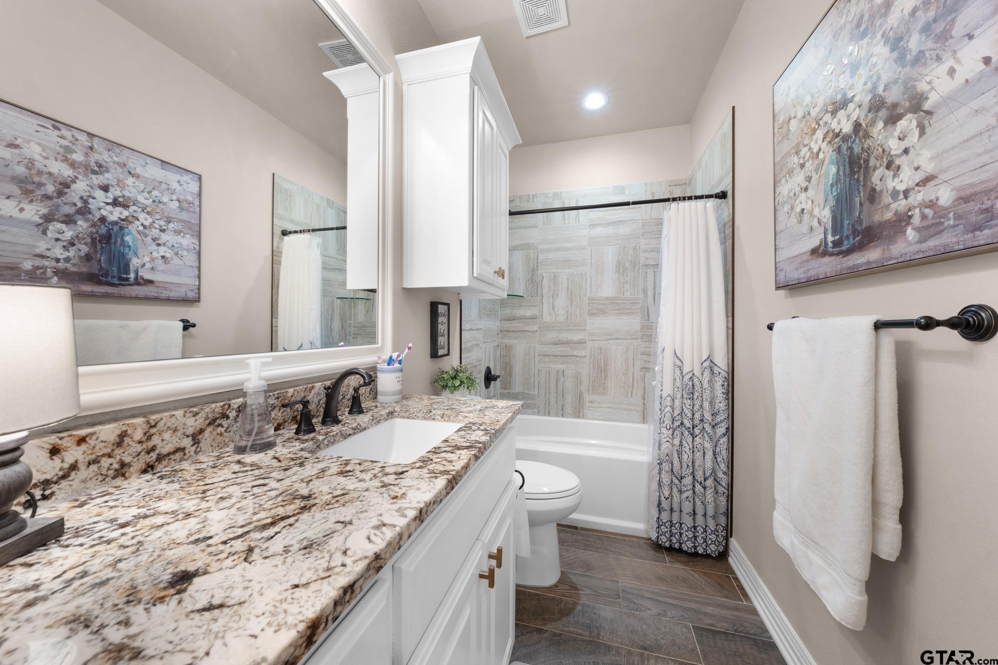 3922 Gable Crest Lane Longview, TX 75605 - Photo 34 of 36 a bathroom with a granite countertop double vanity sink a mirror a bathtub and shower