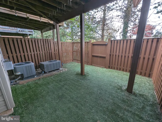 a view of backyard with wooden fence and a large tree