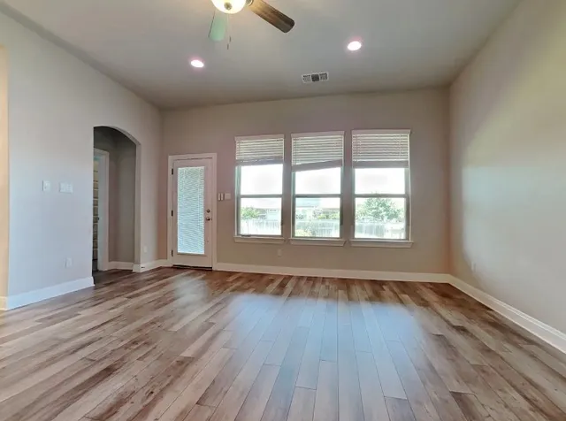 an empty room with wooden floor and windows