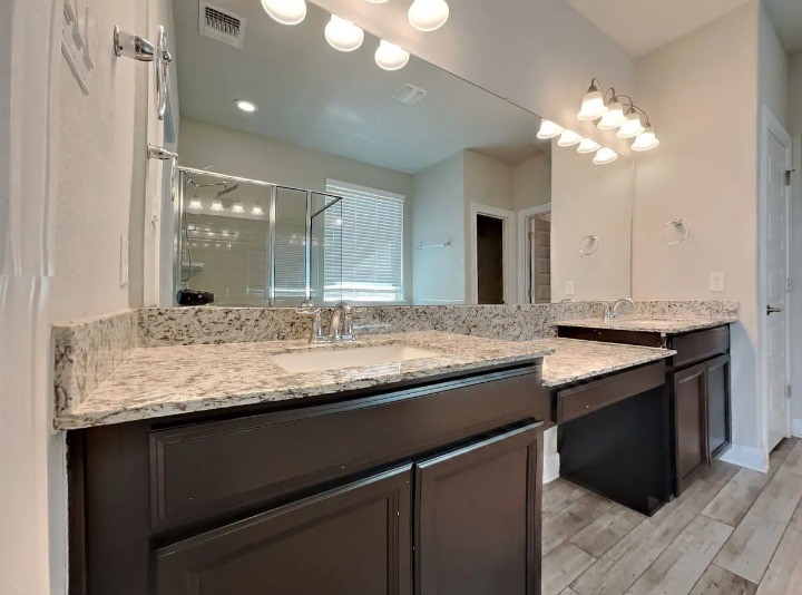 3610 Thunian Pass Pflugerville, TX 78660 - Photo 19 of 27 a bathroom with a granite countertop sink a large mirror and a glass door with shower