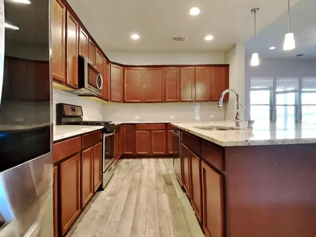 a kitchen with stainless steel appliances granite countertop a sink wooden cabinets and wooden floor