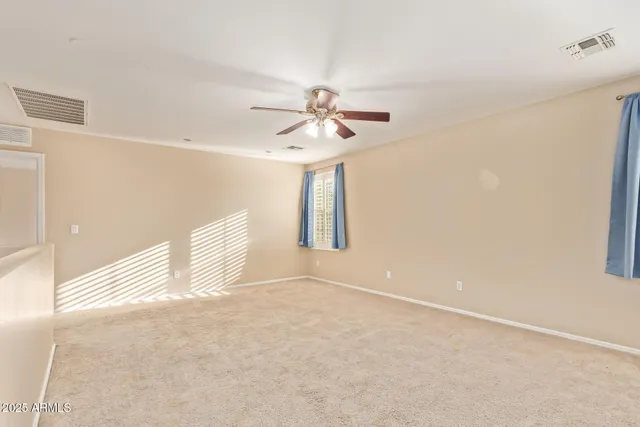 a view of an empty room with chandelier fan and a window