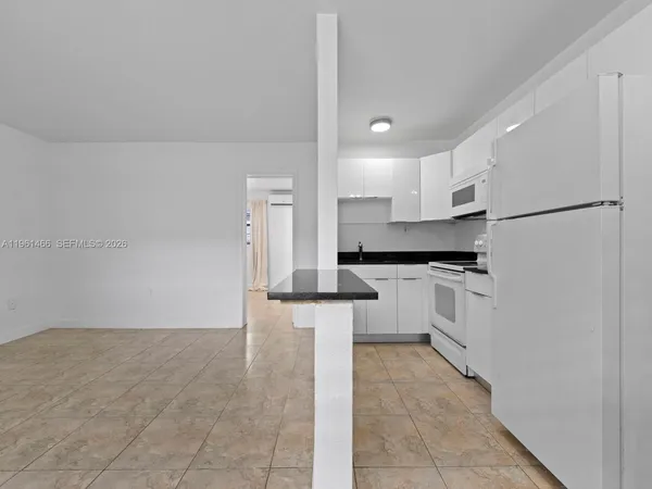 a kitchen with white cabinets and refrigerator