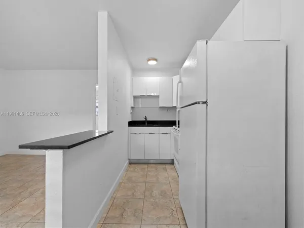 a kitchen with a refrigerator and white cabinets