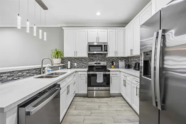 a kitchen with granite countertop a sink stainless steel appliances and white cabinets