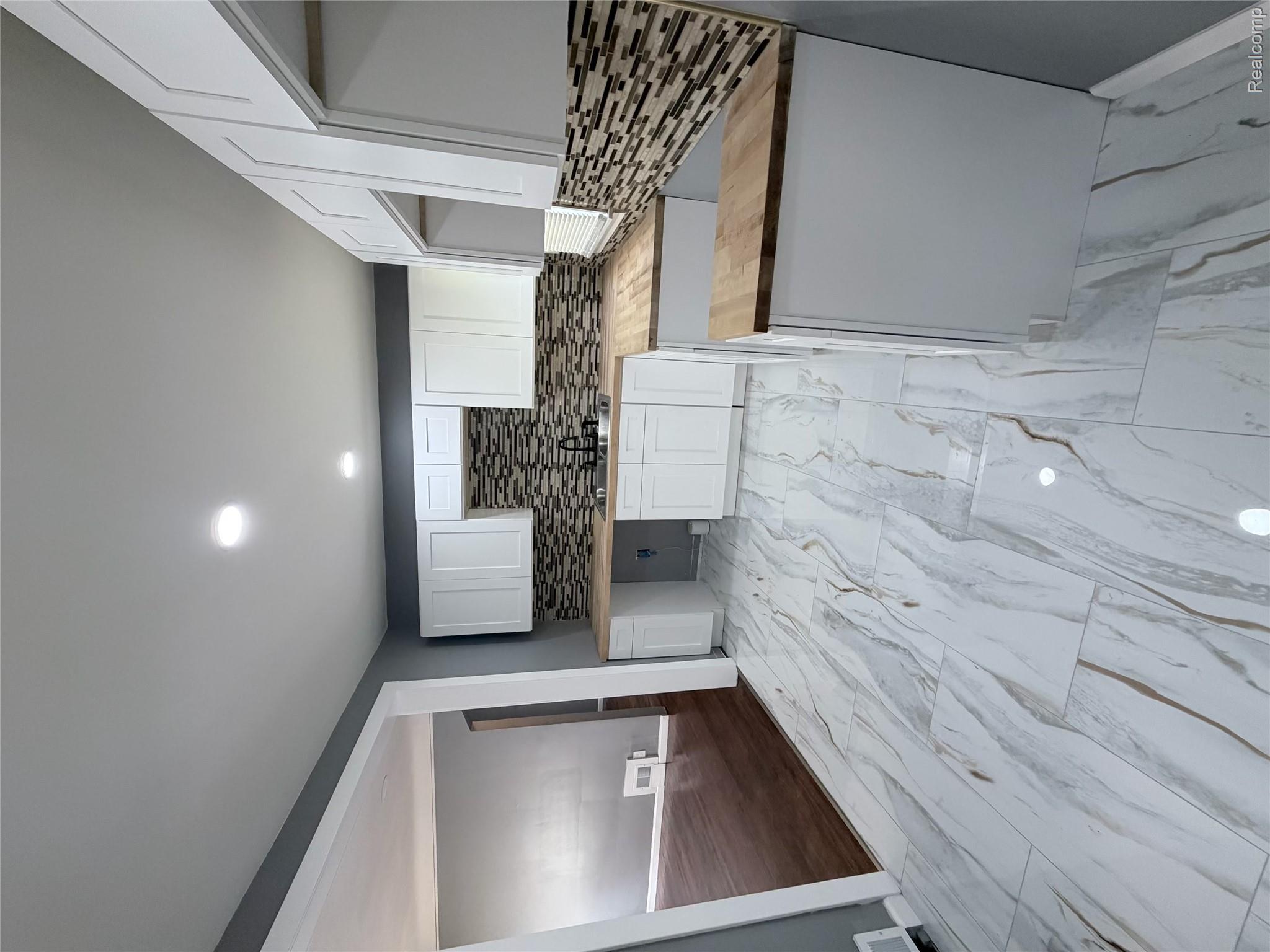 18467 Evergreen Road Detroit, MI 48219 - Photo 5 of 9 White shaker cabinetry with wood-finish countertops, mosaic tile backsplash, stainless steel sink, and recessed lighting
