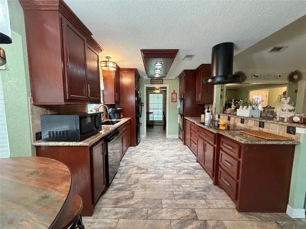 a large kitchen with stainless steel appliances granite countertop a stove refrigerator and cabinets