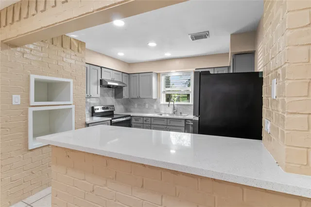 a large kitchen with a large counter top stainless steel appliances and cabinets