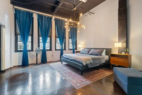 a spacious bedroom with a bed and a chandelier