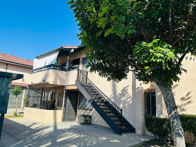 a view of a house with a tree and wooden fence