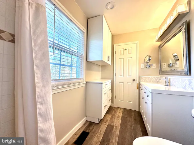 a bathroom with a sink a toilet a mirror and a window