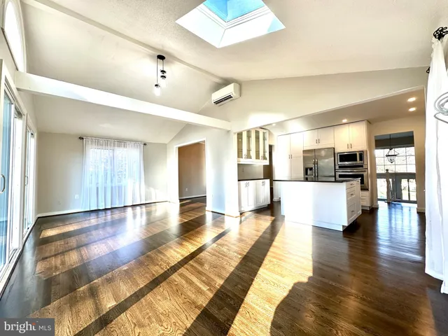 a view of a living room with kitchen view and wooden floor