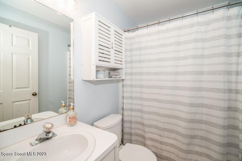 6475 Addax Avenue Cocoa, FL 32927 - Photo 23 of 31 a bathroom with a sink a toilet and shower curtain