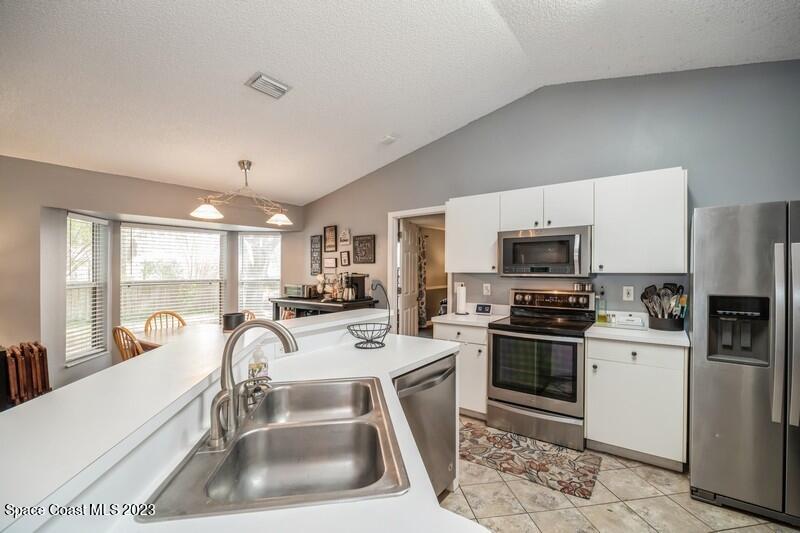 6475 Addax Avenue Cocoa, FL 32927 - Photo 4 of 31 a kitchen with stainless steel appliances a sink a stove a refrigerator cabinets and a dining table with wooden floor