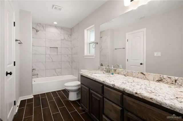 a bathroom with a granite countertop toilet a sink and bathtub
