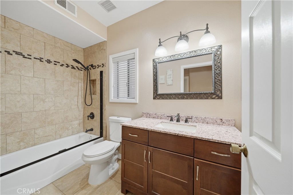 32245 Refa Street Wildomar, CA 92595 - Photo 19 of 69 a bathroom with a granite countertop sink toilet a mirror and shower