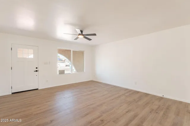 an empty room with wooden floor and windows