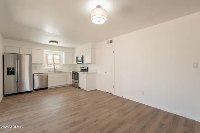 a view of a kitchen with white cabinets and wooden floor