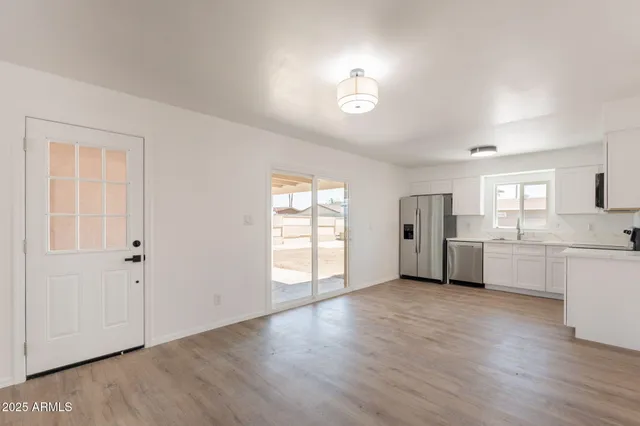 a view of an empty room with a window and wooden floor