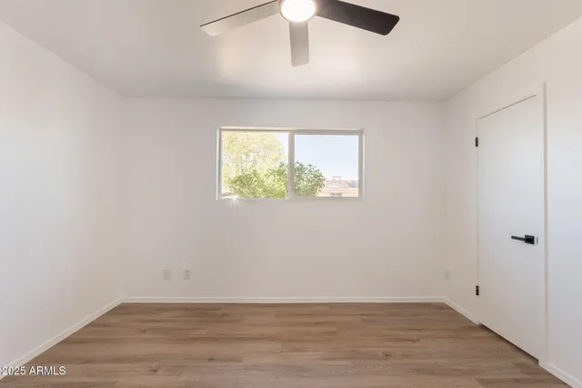 an empty room with wooden floor cabinet and windows