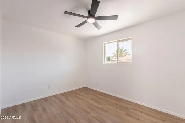 an empty room with wooden floor fan and windows