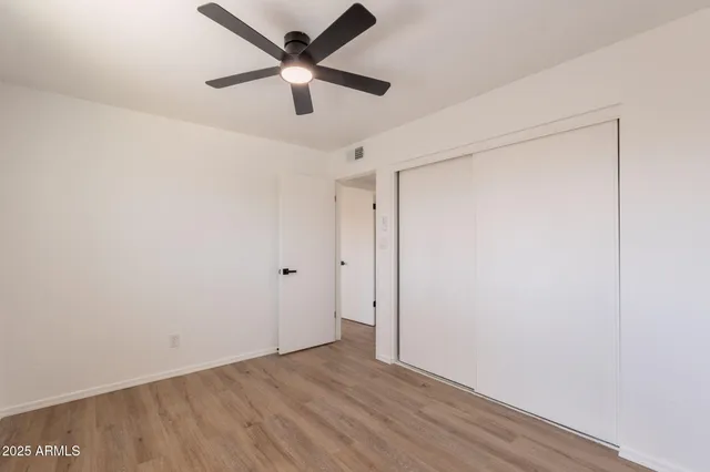 an empty room with wooden floor and a ceiling fan