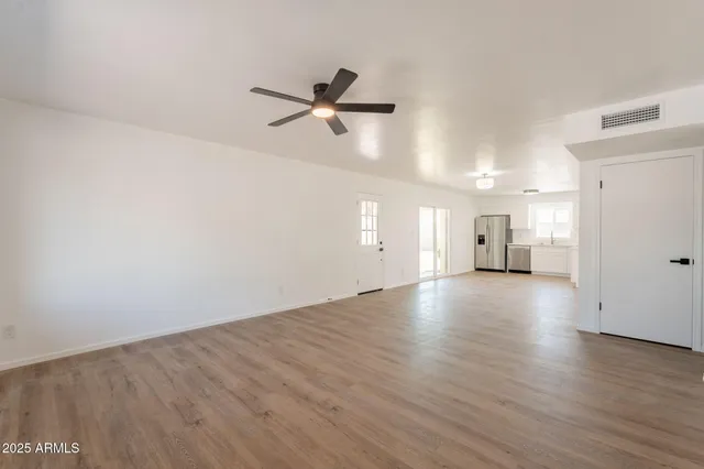 a view of a room with wooden floor and a ceiling fan