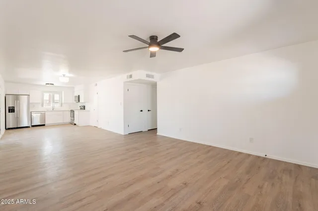 a view of empty room with wooden floor and ceiling fan