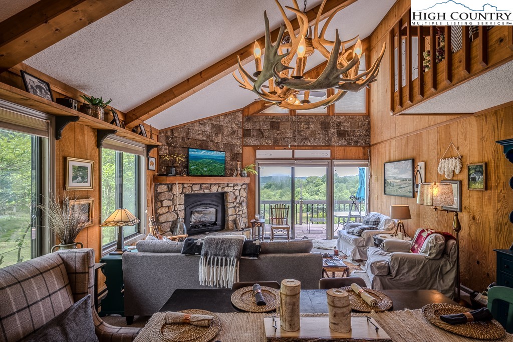 102 Spring Branch Road, Unit E Beech Mountain, NC 28604 - Photo 9 of 40 a living room with furniture a fireplace and a floor to ceiling window