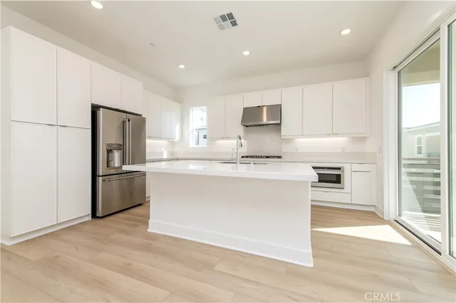 a kitchen with kitchen island a refrigerator stove top oven and sink