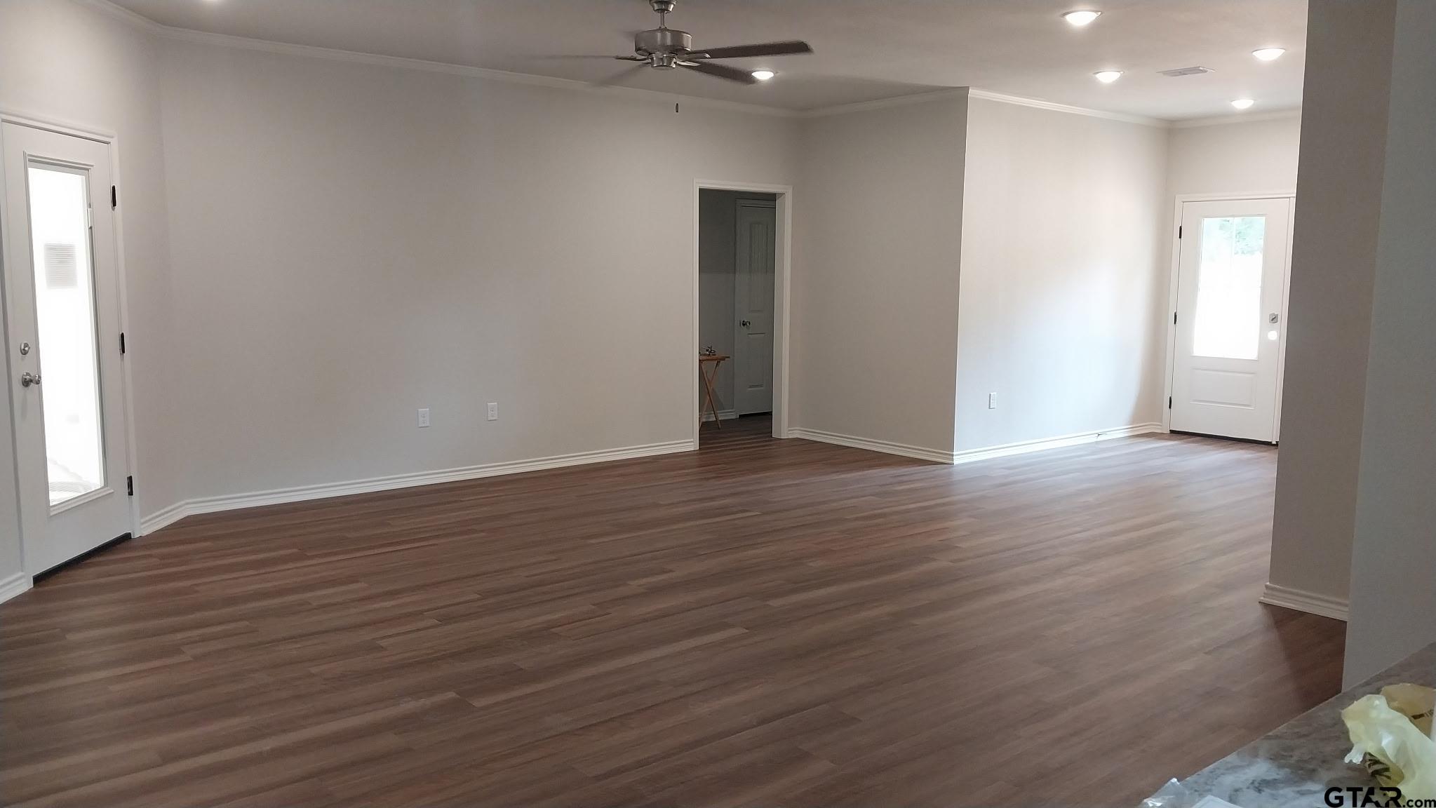 1262 George Richey Road Gladewater, TX 75647 - Photo 4 of 22 an empty room with wooden floor and a hallway