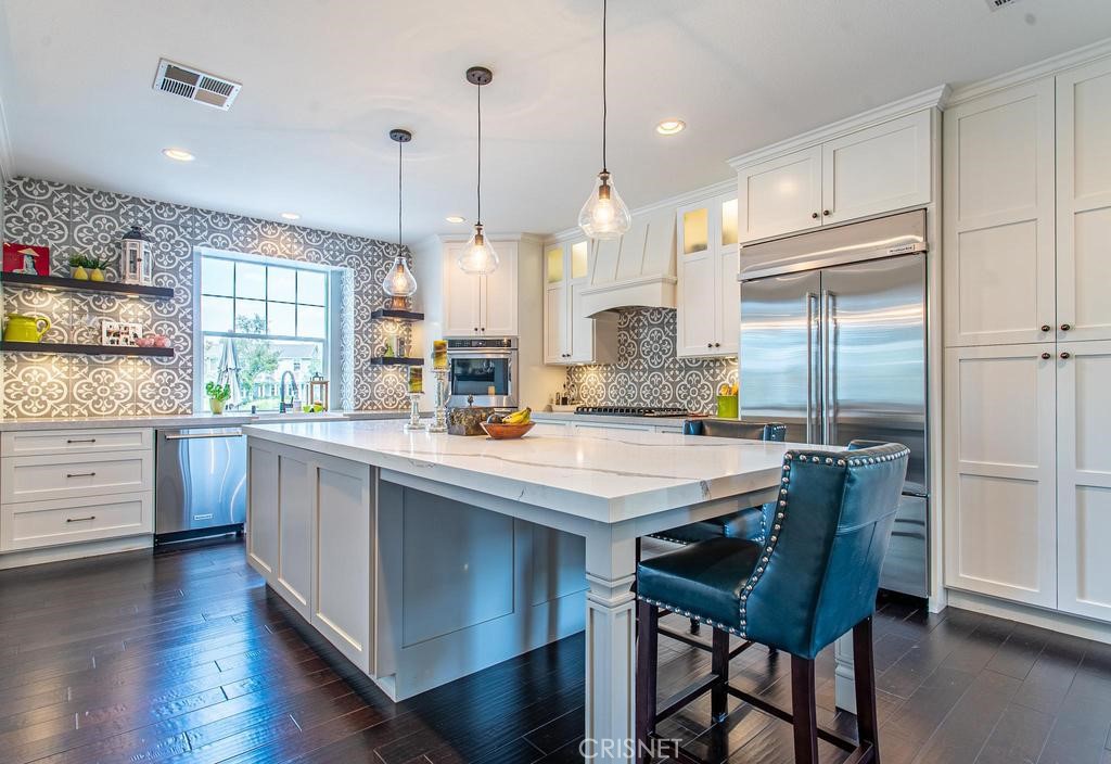 23915 Lakeside Road Valencia, CA 91355 - Photo 31 of 74 a kitchen with stainless steel appliances granite countertop a table chairs stove and kitchen island