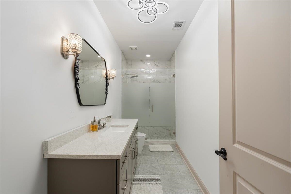 6060 Elmore Road Bartlett, TN 38134 - Photo 31 of 40 Contemporary bathroom featuring a double vanity with stone countertops, integrated sinks, and brushed nickel hardware