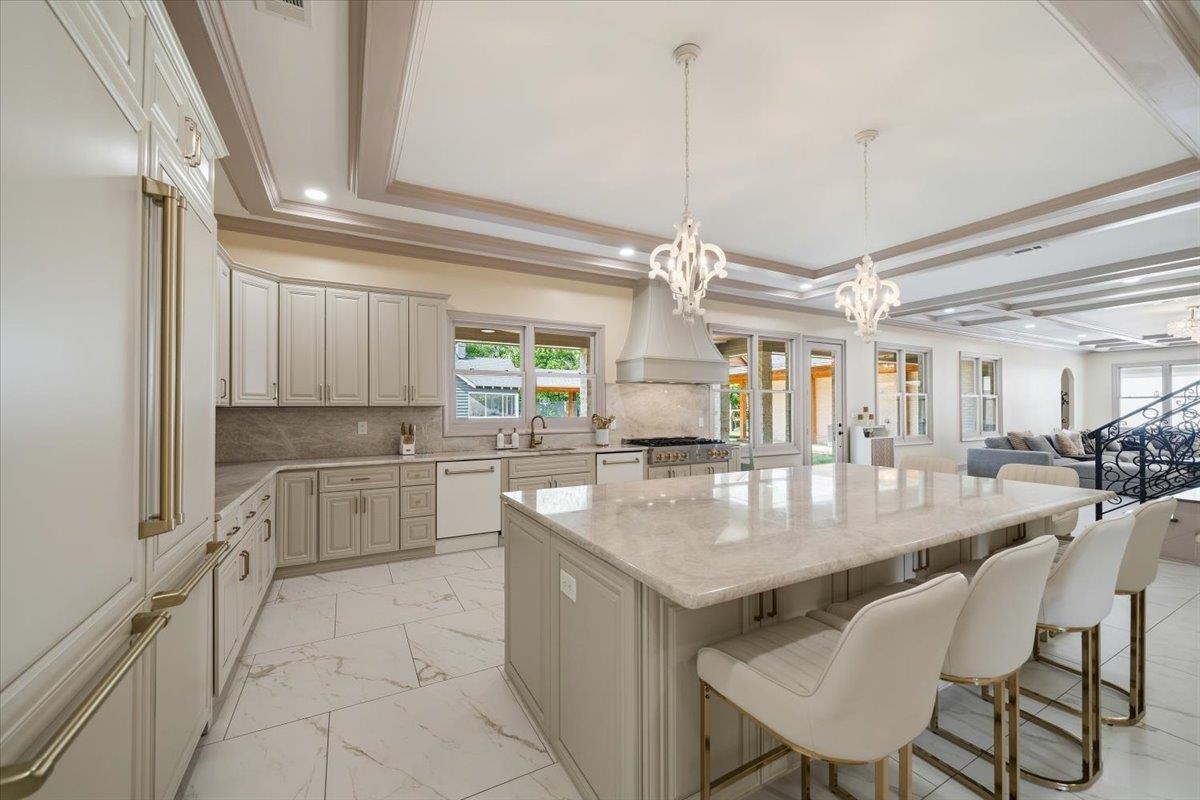 6060 Elmore Road Bartlett, TN 38134 - Photo 8 of 40 Gourmet kitchen featuring a large central island with seating, a professional-grade range with a custom range hood, extensive cabinetry with gold-toned hardware, stone countertops, and sophisticated coffered ceilings