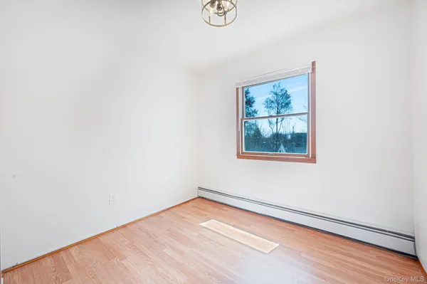 a view of an empty room with wooden floor and window