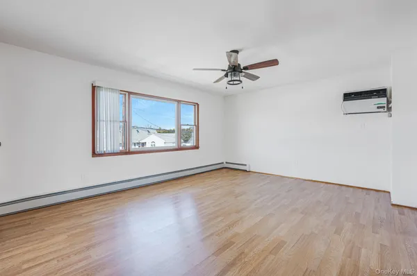 a view of an empty room with window and wooden floor