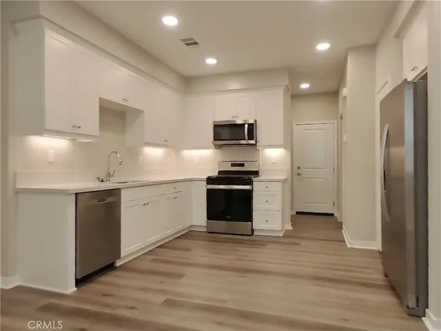 a kitchen with stainless steel appliances kitchen island granite countertop a refrigerator and a stove top oven