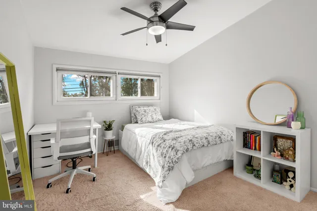 a bedroom with a bed a computer on a desk and a book shelf