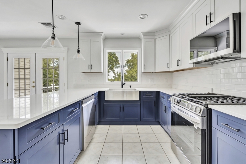 136 Carlough Road Upper Saddle River, NJ 07458 - Photo 10 of 32 a kitchen with stainless steel appliances granite countertop a sink a stove a microwave and wooden cabinets