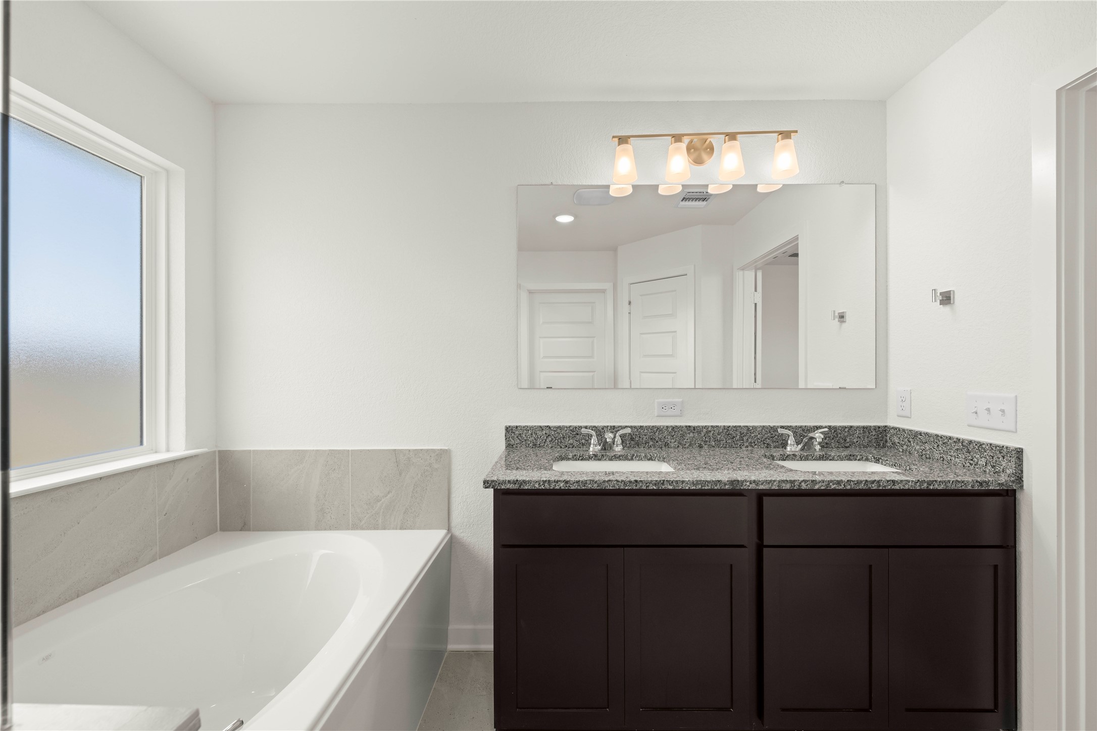 228 Gus Loop Georgetown, TX 78626 - Photo 11 of 19 A well-appointed primary bathroom features a dual vanity with ample counter space alongside a deep soaking tub.