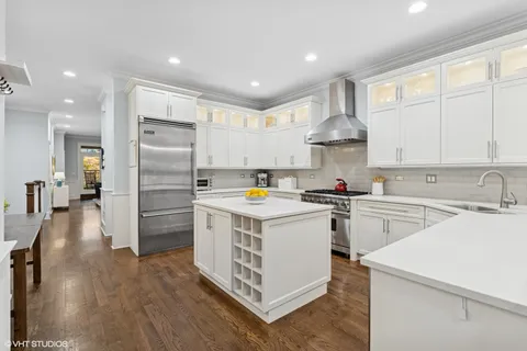 a kitchen that has a lot of white cabinets and stainless steel appliances