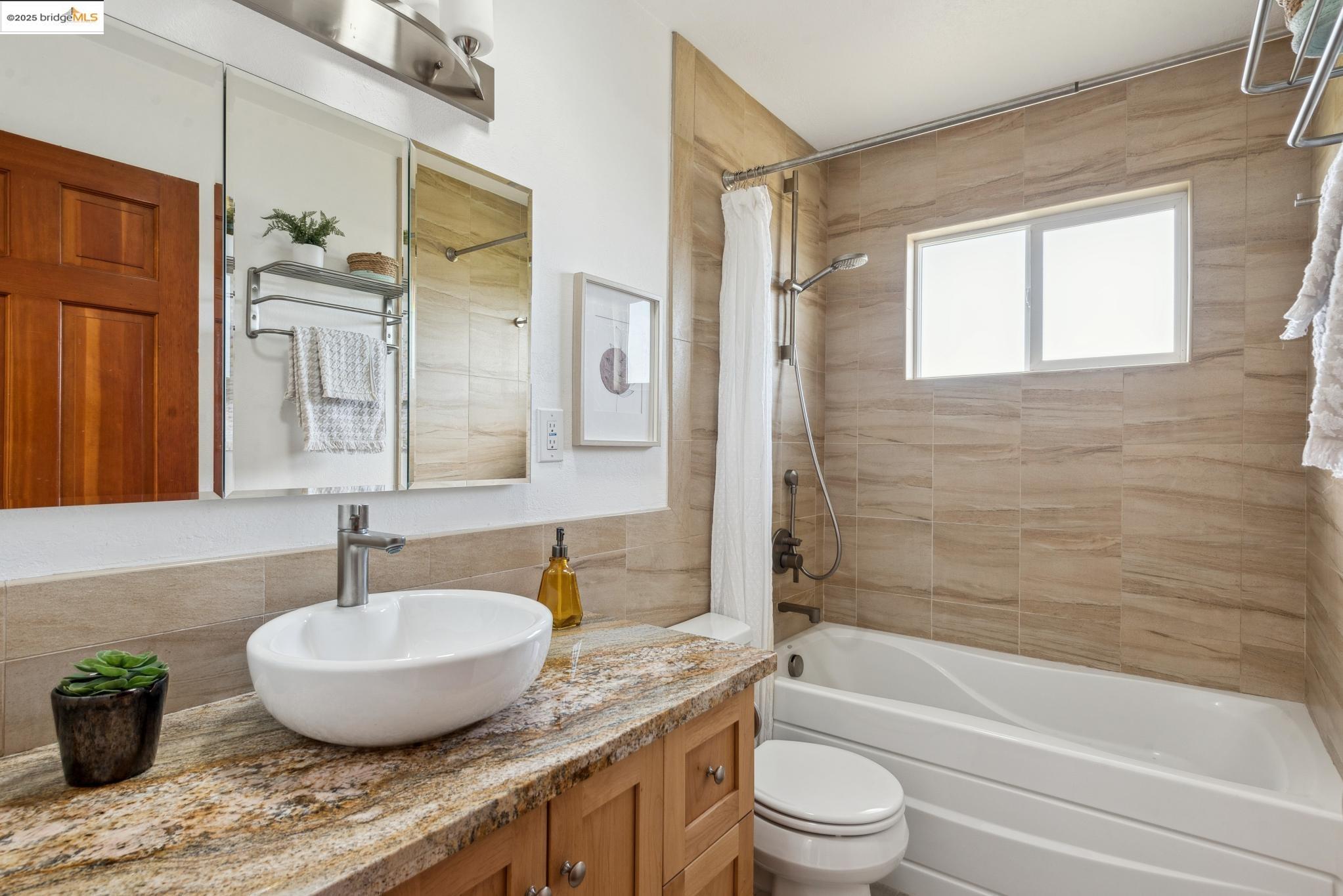 Undisclosed Address San Leandro, CA 94577 - Photo 28 of 50 a bathroom with a granite countertop sink a toilet a mirror and bathtub