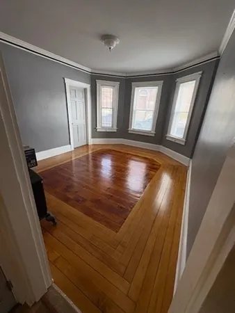 a view of empty room with window and wooden floor