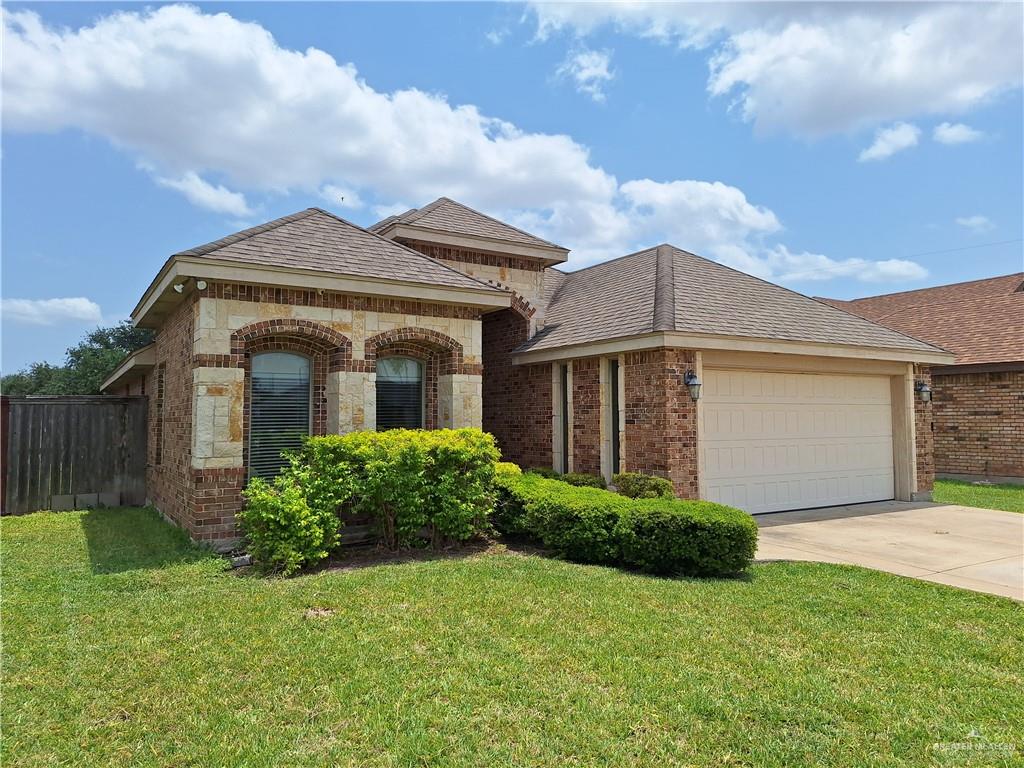 2212 North Ruby Street Edinburg, TX 78541 - Photo 2 of 11 View of front of house featuring fence, a front lawn, brick siding, a garage, and driveway