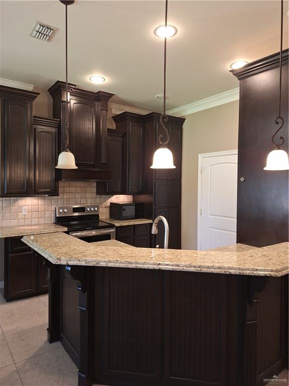 2212 North Ruby Street Edinburg, TX 78541 - Photo 9 of 11 Kitchen featuring a breakfast bar area, light stone counters, range, tasteful backsplash, and ornamental molding