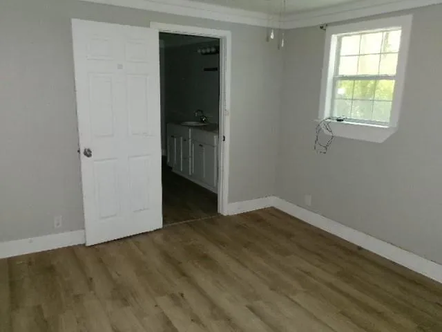 an empty room with wooden floor closet and windows