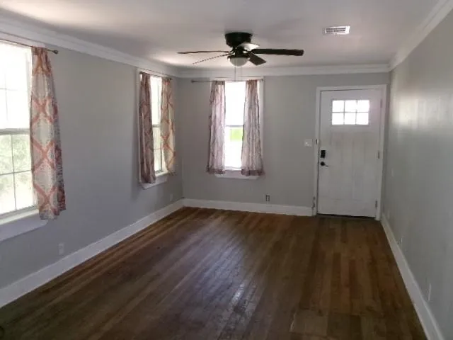 a view of an empty room with wooden floor and a window