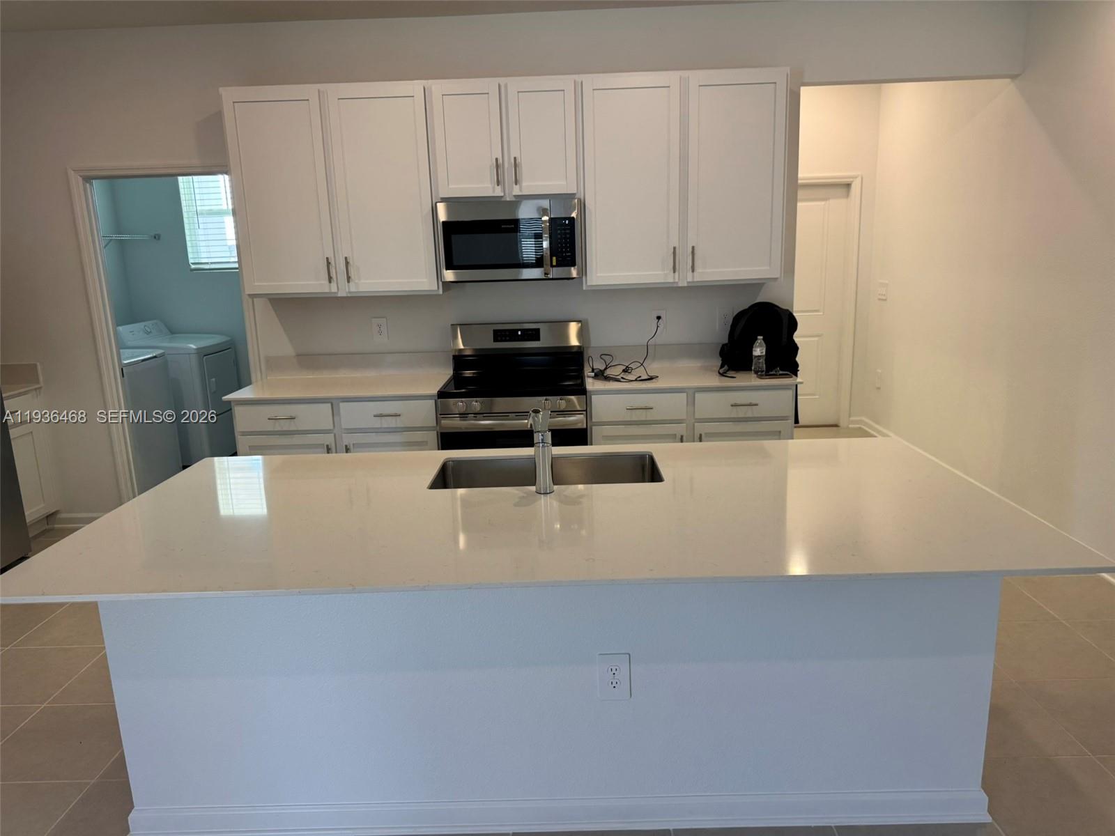 2517 Spring Tune Alley Kissimmee, FL 34744 - Photo 7 of 16 a kitchen with kitchen island sink stove and white cabinets