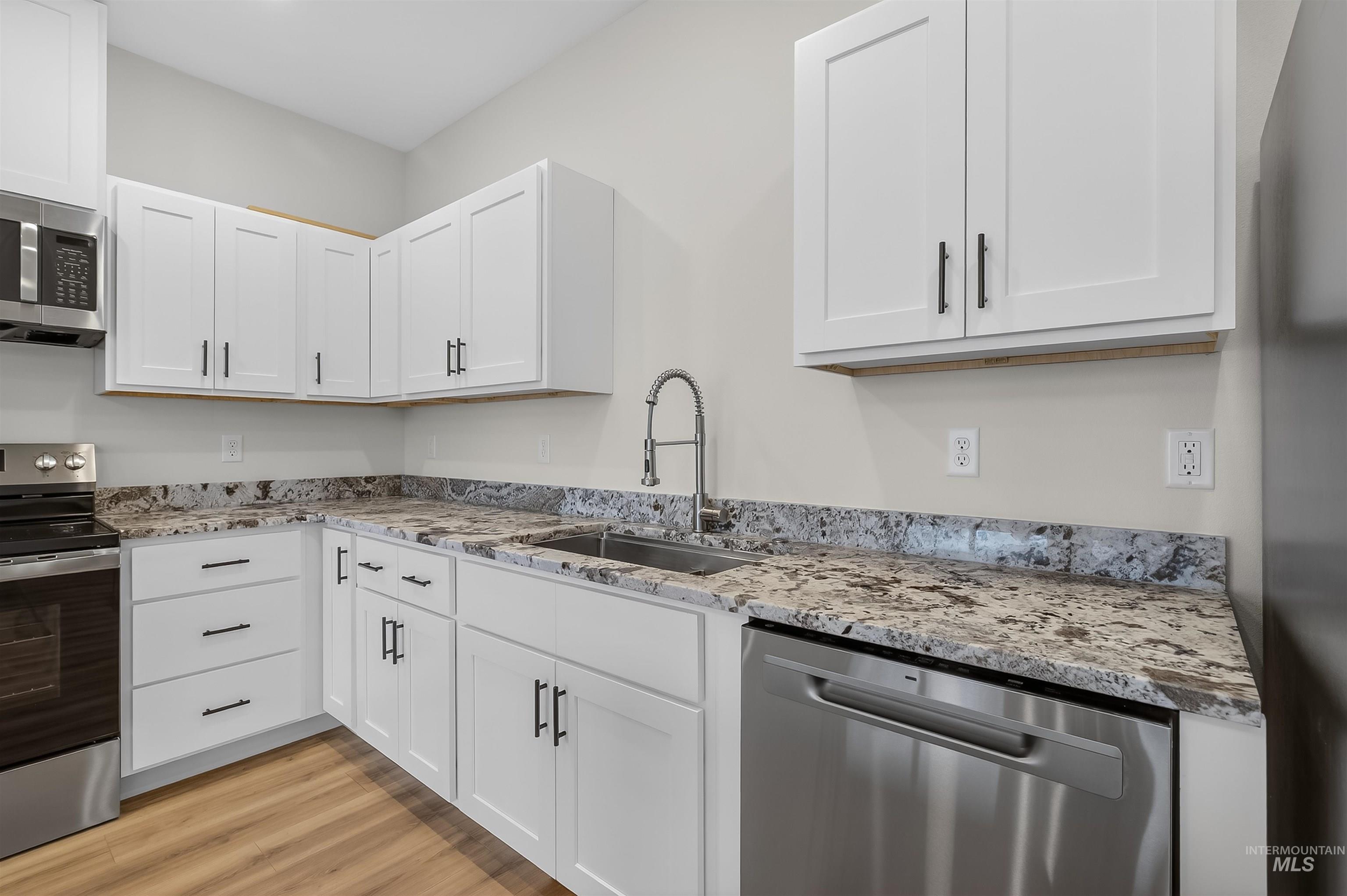 606 Warner Avenue, Unit B Lewiston, ID 83501 - Photo 12 of 38 Kitchen featuring stainless steel appliances, white cabinetry, light stone countertops, and light wood-type flooring
