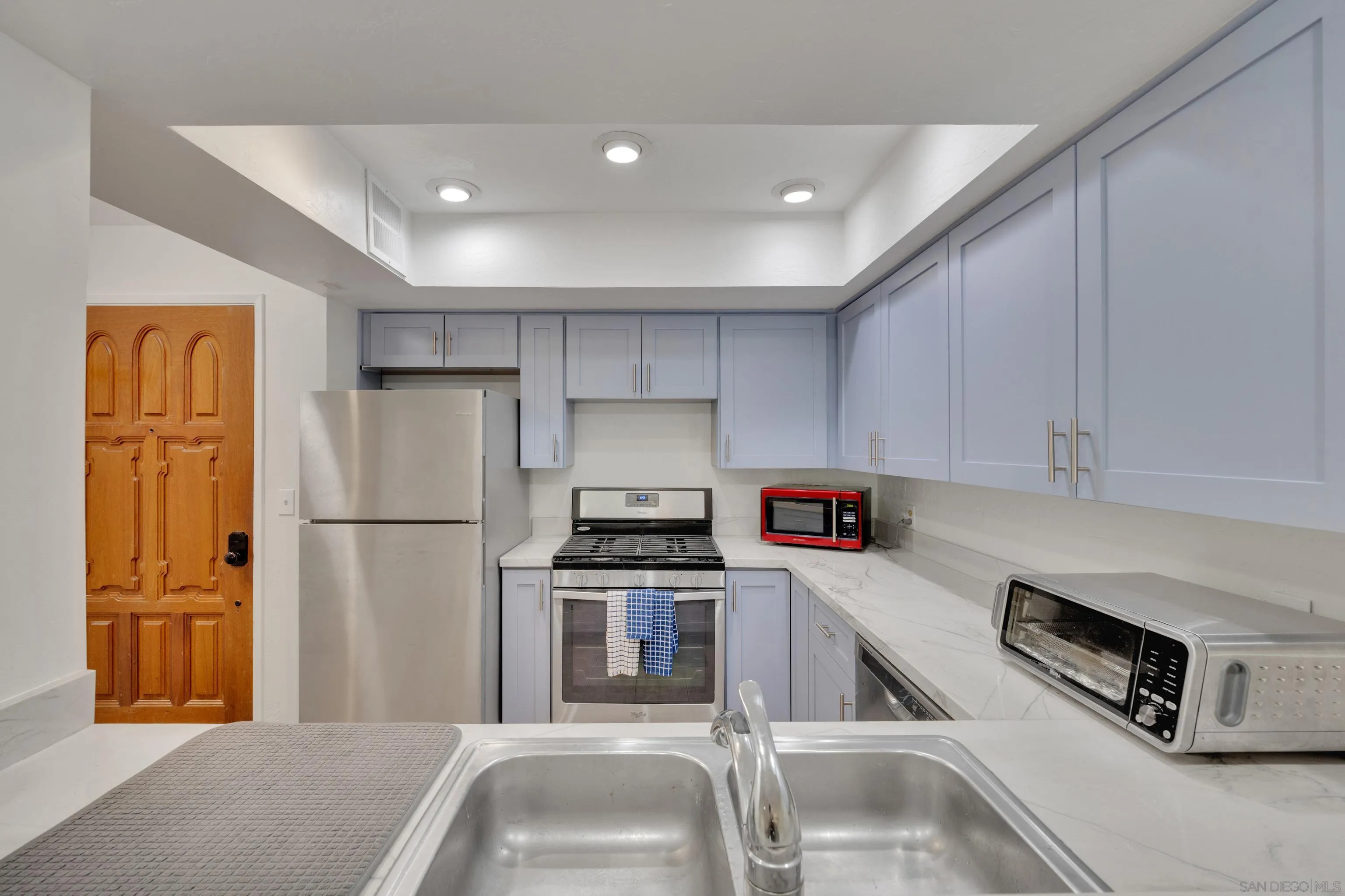 4055 Falcon Street, Unit 102 San Diego, CA 92103 - Photo 6 of 36 a kitchen with a refrigerator a stove top oven and white cabinets